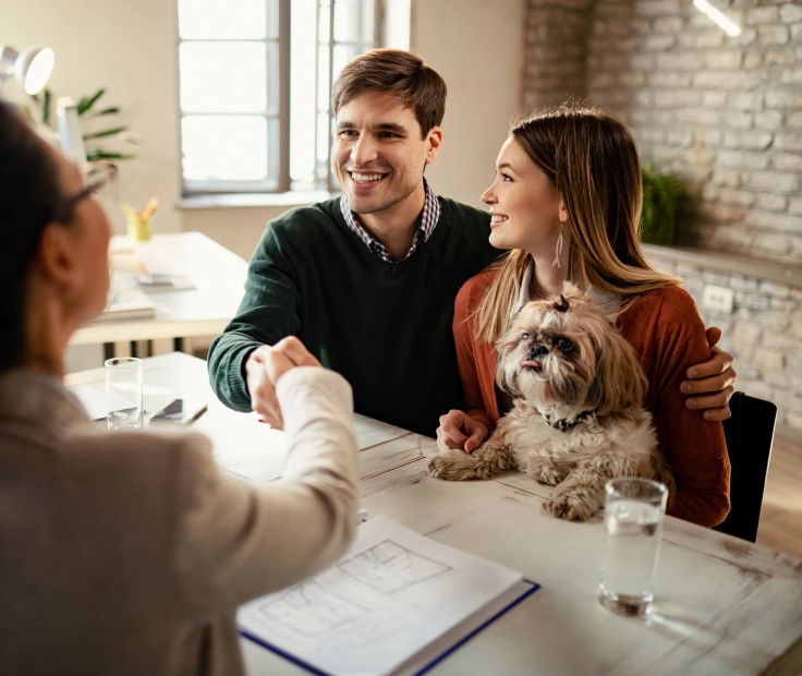 happy-couple-with-dog-shaking-hands-with-real-estate-agent-office
